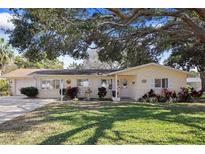 Charming single-story home with manicured lawn and mature trees in a desirable neighborhood at 1549 San Christopher Dr, Dunedin, FL 34698