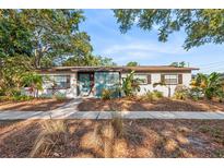 Charming single-story home featuring a brick exterior, lush landscaping, and a welcoming blue front door at 810 22Nd N St, St Petersburg, FL 33713