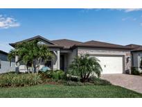 Beautiful single-story home featuring stone accents, manicured lawn, and a two-car garage at 8724 Ocean Tides Cv, Parrish, FL 34219