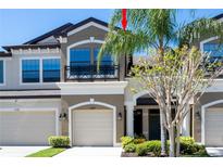 A charming multi-story townhouse boasting a private garage and a quaint balcony with black iron railings at 11648 Crowned Sparrow Ln, Tampa, FL 33626