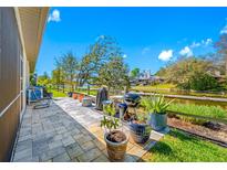 Relaxing back patio featuring a grill and a beautiful view of the tranquil waterway and the house across it at 2270 Spring Lake Ct, Clearwater, FL 33763