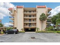 Multi-story condo building with red tile roof, covered parking and tropical landscaping at 2700 Bayshore Blvd # 9404, Dunedin, FL 34698