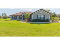 Well-maintained single-story home featuring a lush green lawn and mature landscaping at 27941 Austin Woods Dr, Dade City, FL 33525