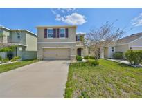 Two-story home featuring a two car garage, neutral paint, and tidy landscaping under a blue sky at 10967 Carlton Fields Dr, Riverview, FL 33579