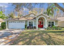 Charming single-story home with a red front door, attached garage, and well-maintained landscaping at 4932 Wellbrook Dr, New Port Richey, FL 34653