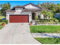 Beautiful single-story home with a well-manicured lawn, mature landscaping, and a two car garage at 5016 Bella Armonia Cir, Wimauma, FL 33598