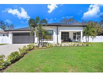 Charming single-story home featuring a manicured lawn, lush landscaping, and a two-car garage at 7403 Edgemere Rd, Tampa, FL 33625