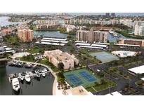 Wide aerial view of community featuring a pool, tennis courts, parking, waterway, and residences at 7910 Sun Island S Dr # 302, South Pasadena, FL 33707