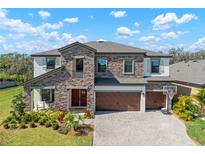 Beautiful two-story home showcasing stone accents, a three-car garage and manicured lawn at 13103 Wildflower Meadow Dr, Riverview, FL 33579