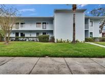 Two-story condo building with well-maintained lawn and a palm tree in a tropical setting at 313 Martha Ln # 4, Oldsmar, FL 34677