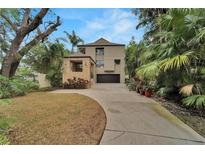 Contemporary two-story home featuring modern architecture, dark garage door, a stone-accented entry, and lush tropical landscaping at 4035 N River View Ave, Tampa, FL 33607