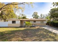 Charming single-story home featuring a well-manicured lawn, mature trees, and a classic exterior design at 6125 Liberty Ave, Temple Terrace, FL 33617