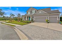 Stunning two-story home featuring a three-car garage, blue door, and beautifully landscaped front yard at 7820 Marsh Pointe Dr, Tampa, FL 33635