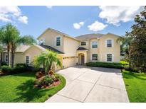 Inviting two-story home with a well-manicured lawn, a circular driveway, and a two-car garage at 9614 Orange Jasmine Way, Tampa, FL 33647