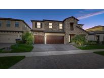 Stunning two-story home featuring a stone facade, three-car garage, and well-maintained landscaping at 12857 Satin Lily Dr, Riverview, FL 33579
