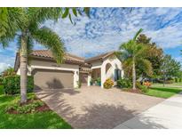 Charming home featuring a brick driveway, a two-car garage, and professionally landscaped garden with palm trees at 14315 Rolling Dune Rd, Lithia, FL 33547