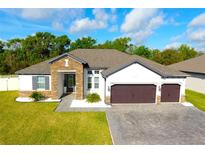 Beautiful single-story home with stone accents, a well-manicured lawn, and a paver driveway at 19730 Preservation Woods Dr, Lutz, FL 33558