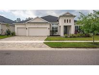 Elegant home features a three-car garage, well-manicured lawn, and contemporary architectural details at 4206 Tour Trce, Land O Lakes, FL 34638