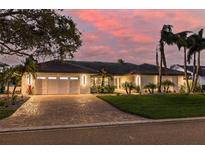 Beautiful single-story home featuring a white exterior, well-manicured lawn, brick driveway and lush landscaping at 4959 58Th S Ave, St Petersburg, FL 33715