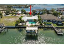 Waterfront home featuring a private dock, boat lift, and swimming pool on a sunny day at 5105 W Longfellow Ave, Tampa, FL 33629