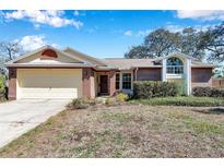 Charming single-story brick home with attached garage and a well-manicured lawn at 8137 Greenside Ln, Hudson, FL 34667
