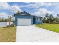Bright blue single-story home featuring a two-car garage and well-manicured lawn at 9510 Xenia St, New Port Richey, FL 34654