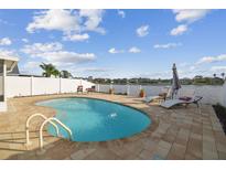 Sparkling in-ground pool with a brick paver patio, lounge chairs and scenic water views at 10610 Lakeside Vista Dr, Riverview, FL 33569