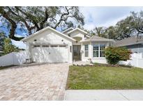 Charming single-story home with a brick driveway, lush lawn, and neutral-toned exterior paint at 3405 W Cherry St, Tampa, FL 33607
