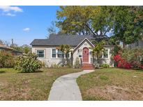 Charming bungalow-style home featuring a red front door, lush landscaping, and a curved walkway at 511 27Th N Ave, St Petersburg, FL 33704