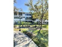 Well-maintained condo building with mature trees, landscaping and a comfortable bench at 8080 112Th St # 206, Seminole, FL 33772