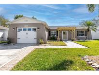 Charming single-story home with a well-manicured lawn, a two-car garage, and a covered front porch at 11045 Broadwood N Dr, Pinellas Park, FL 33782