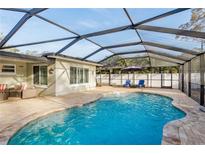 Enclosed pool with brick patio, seating, and sunshades, creating a comfortable outdoor living area at 2005 Harvard Ave, Dunedin, FL 34698