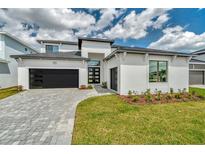 Modern home featuring a black garage door, monochromatic color scheme, and paver driveway at 32347 Wetland Bird Vw, San Antonio, FL 33576