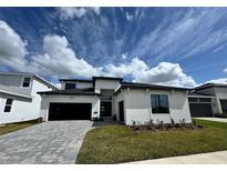 Modern two-story home featuring a paved driveway, black garage door, and well-manicured lawn at 32347 Wetland Bird Vw, San Antonio, FL 33576