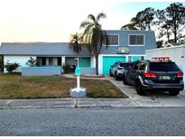 Charming two-story home with gray and white exterior, turquoise doors, and mature landscaping at 3519 Richboro Dr, Holiday, FL 34691