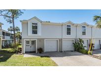 Charming townhome featuring a two-car garage, a well-manicured lawn, and a welcoming double-door entrance at 7631 Sailwinds Pass, Port Richey, FL 34668