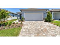 Beautiful single-Gathering home featuring a two-car garage and charming landscaping, plus a brick paver driveway and walkway at 9412 Coastline Way, Parrish, FL 34219