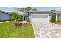 Charming home exterior features a two-car garage, landscaped yard, and brick paver driveway at 9466 Shorebird Ct, Parrish, FL 34219