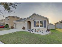 Inviting home with manicured lawn, garden bed, stone walkway, and a two-car garage at 12029 Gillingham Harbor Ln, Gibsonton, FL 33534