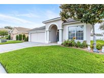 Charming one-story home featuring a well-manicured lawn, an arched entry, and a two car garage at 16313 Dinsdale Dr, Spring Hill, FL 34610