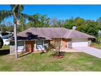 Charming single-story home with a well-manicured lawn, mature trees, and attached two car garage at 17010 Aspen Meadows Dr, Lutz, FL 33548