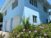 Light blue two story home featuring white garage doors and front yard garden filled with purple flowers at 1800 Pass A Grille Way # 5, St Pete Beach, FL 33706