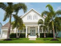 Charming two-story home with a manicured lawn and tropical palm trees surrounding the property at 413 Islebay Dr, Apollo Beach, FL 33572