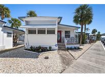 Charming single-story home with a red door, covered porch, palm trees, and landscaped front yard at 4851 W Gandy Blvd # B7L9, Tampa, FL 33611