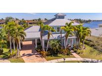 Stunning waterfront home featuring a metal roof, mature palms, and well-maintained landscaping at 5321 Fishersound Ln, Apollo Beach, FL 33572