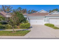 Charming home showcasing a manicured lawn, mature trees, and an attached two-car garage, reflecting a peaceful suburban setting at 13574 Circa Crossing Dr, Lithia, FL 33547
