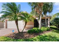 Charming single-story home featuring well-kept landscaping, palm trees, and a brick-paved walkway at 15908 Cobble Mill Dr, Wimauma, FL 33598