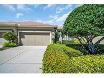 Inviting home exterior featuring a two-car garage, tiled roof, lush landscaping, and a well-maintained driveway at 2537 Gloriosa Dr # 2, Palm Harbor, FL 34684