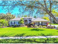 Beautifully landscaped home with lush green lawn, mature trees, and colorful flowerbeds enhance curb appeal at 7546 Dunbridge Dr, Odessa, FL 33556