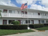 Two-story apartment building with white facade, an American flag, and well-maintained landscaping at 8220 112Th St # 202, Seminole, FL 33772